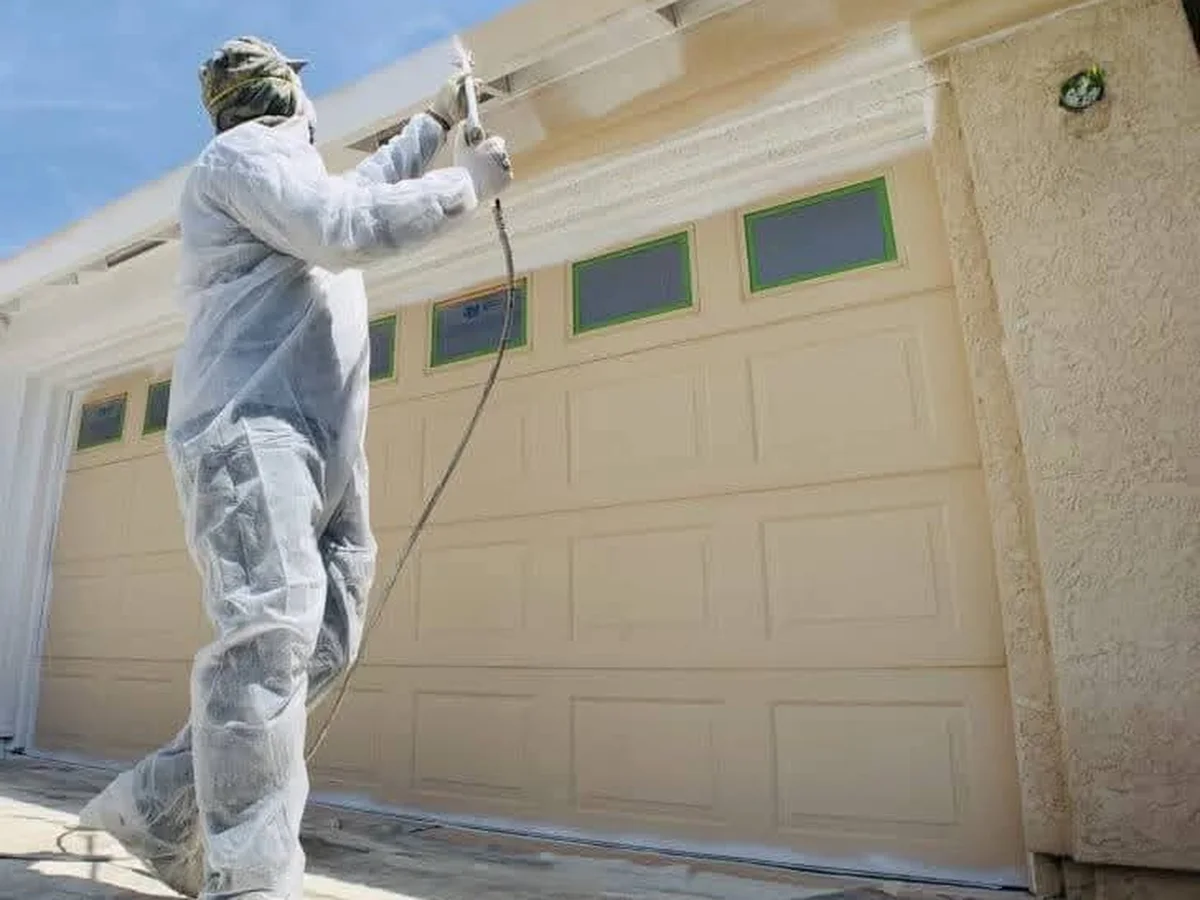 Spraying a garage door and exterior trim in a protective suit